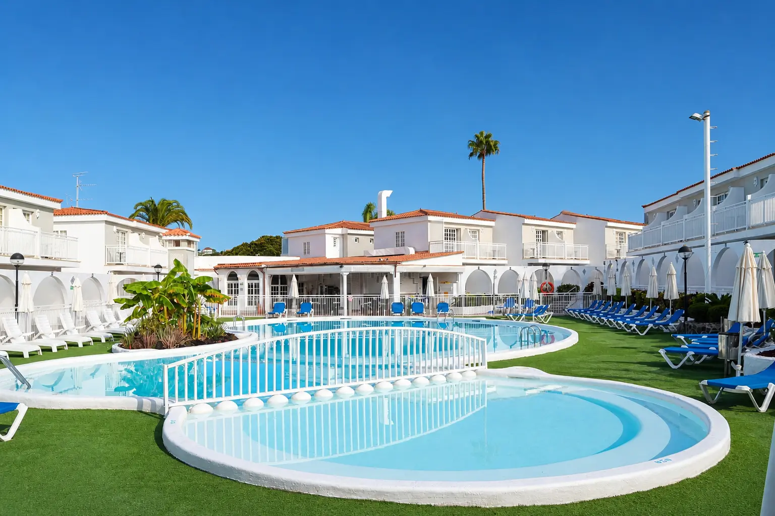 Piscina exterior de Parque Nogal rodeada de bungalows blancos